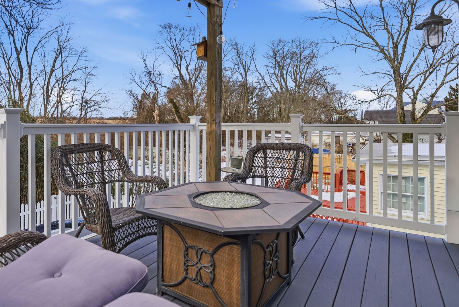 Second-floor deck with fire table and wicker chairs
