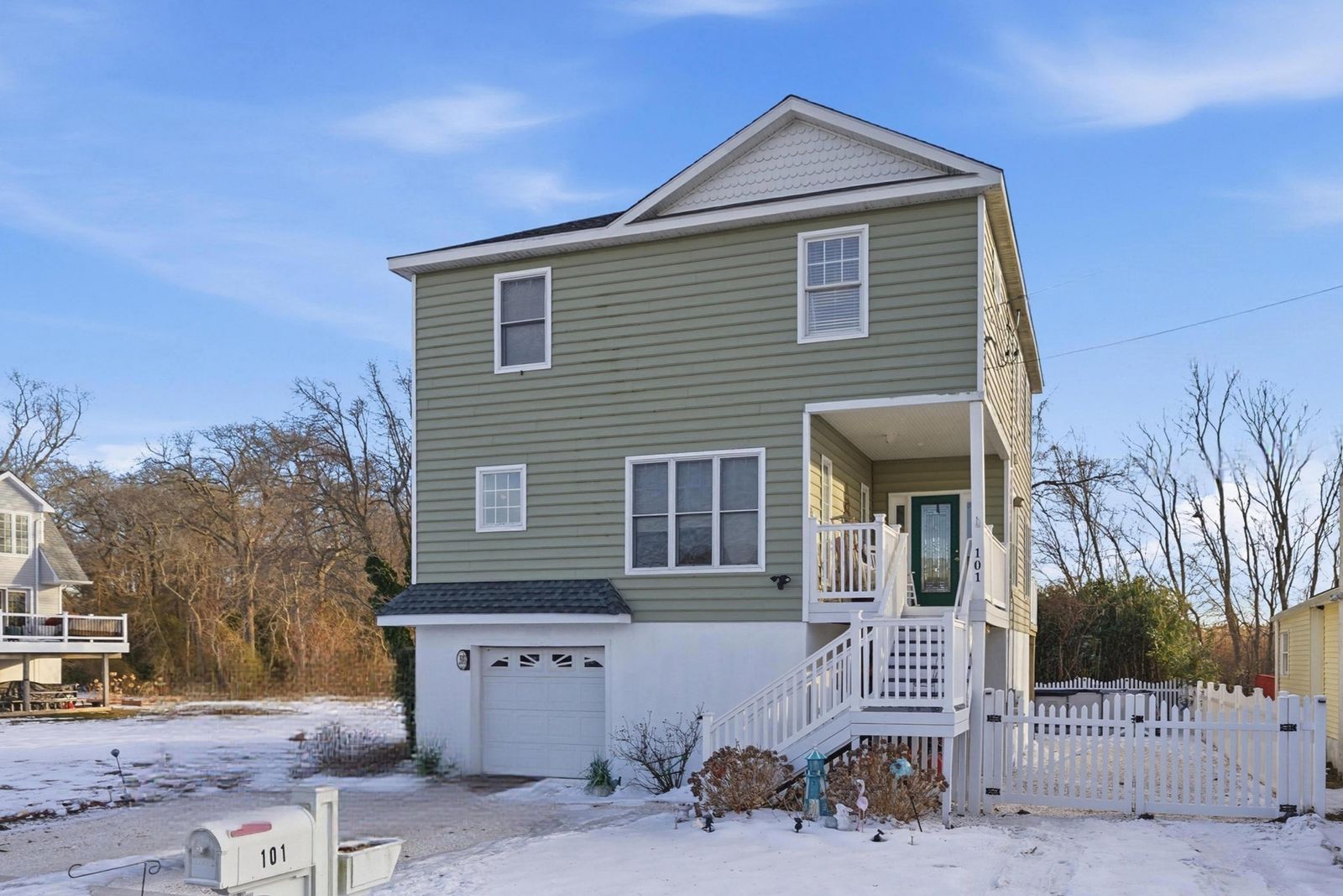 Green two-story Villas NJ home with garage and front stairs