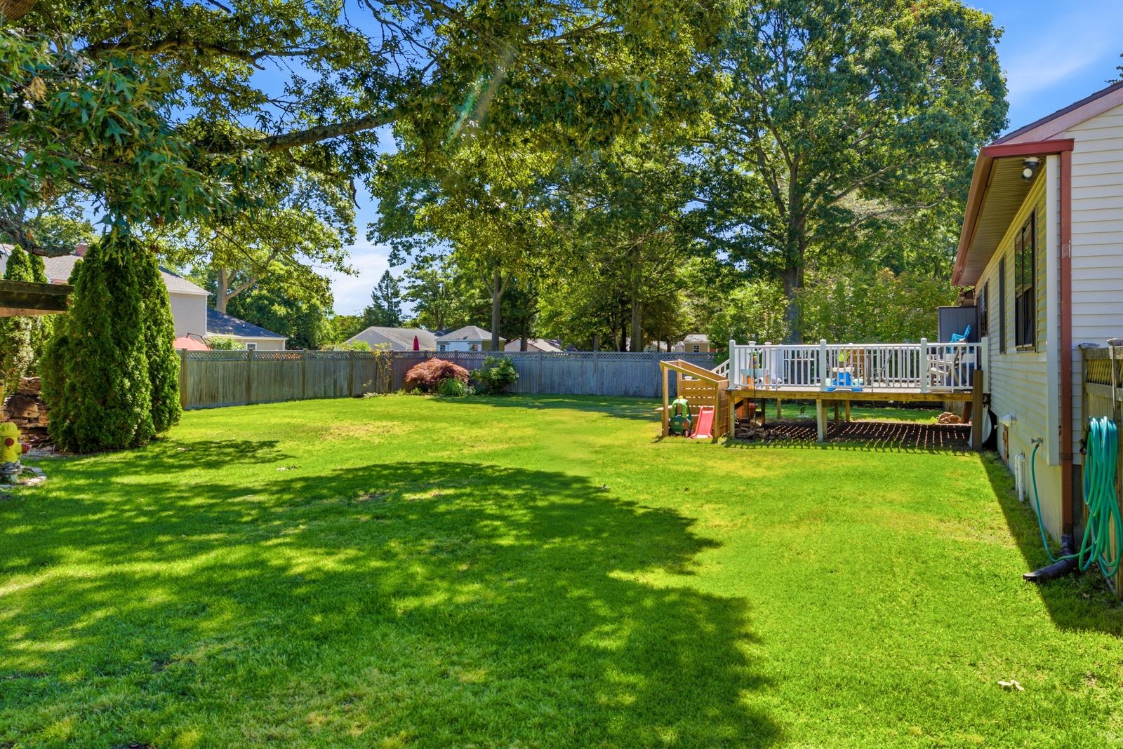 Fenced backyard lawn with mature trees and the back deck in Cape May Court House NJ