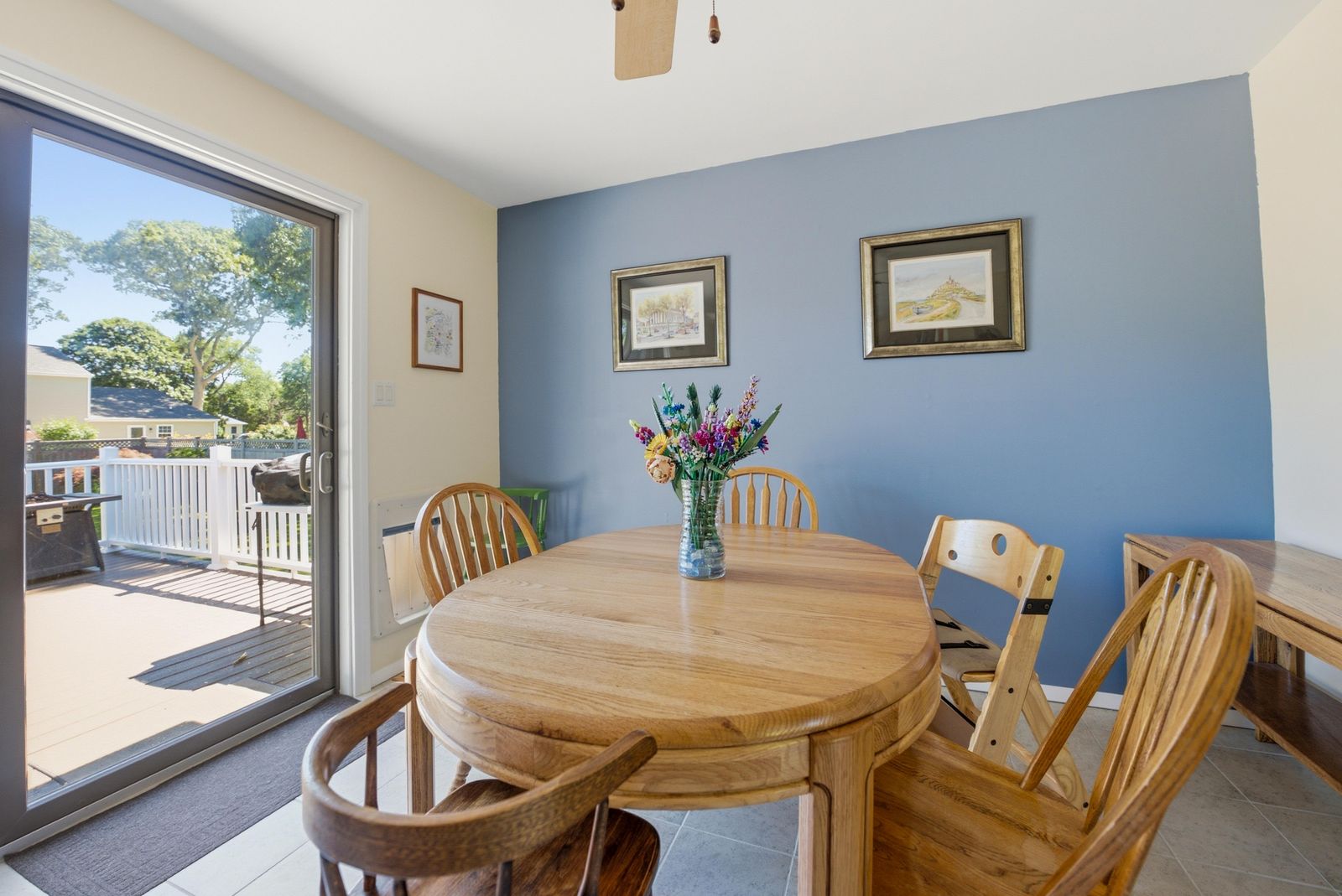 Dining area with round oak table, blue accent wall and sliding door to the deck in Cape May Court House NJ