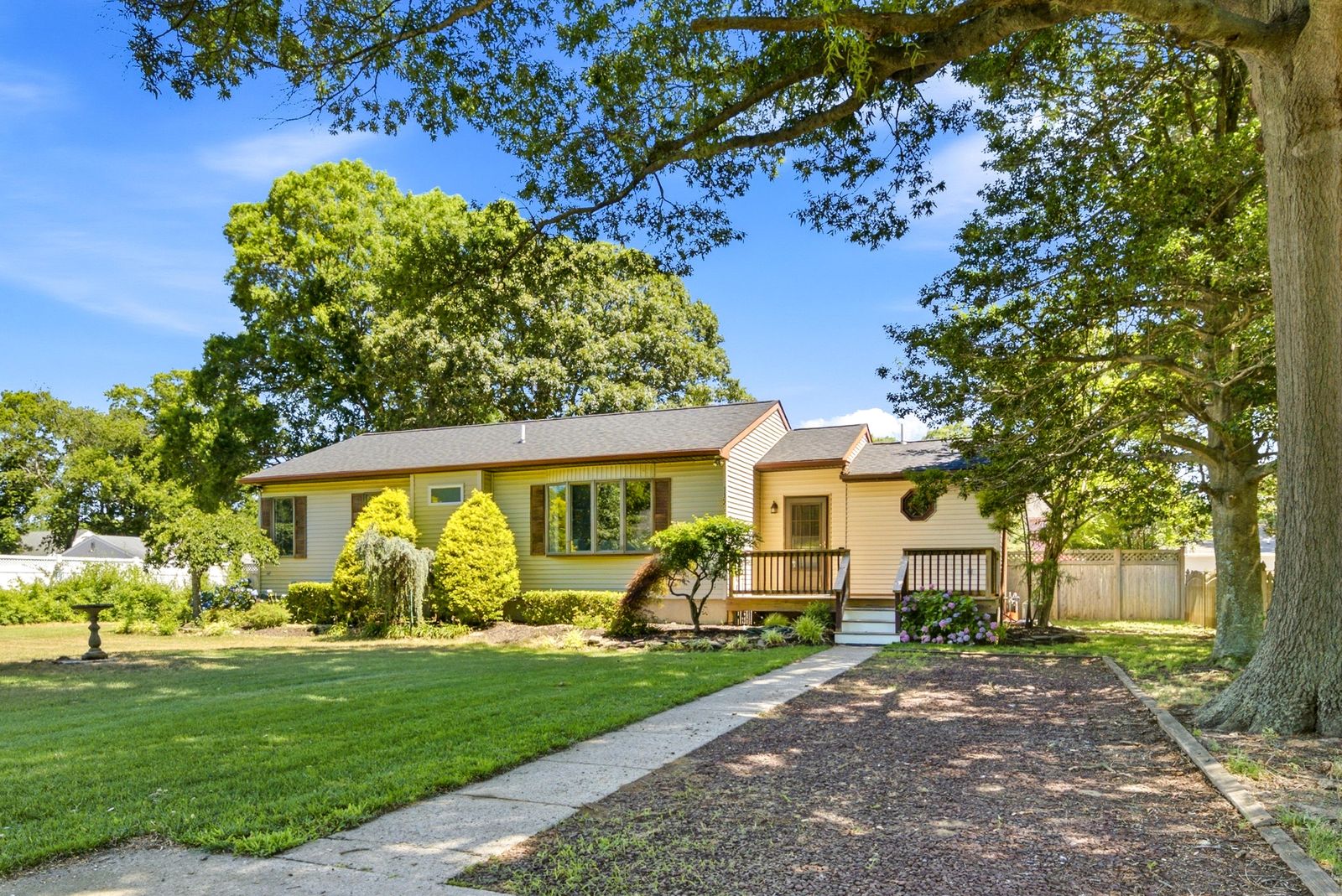 Yellow ranch home with front deck, hydrangeas and a large shade tree in Cape May Court House NJ