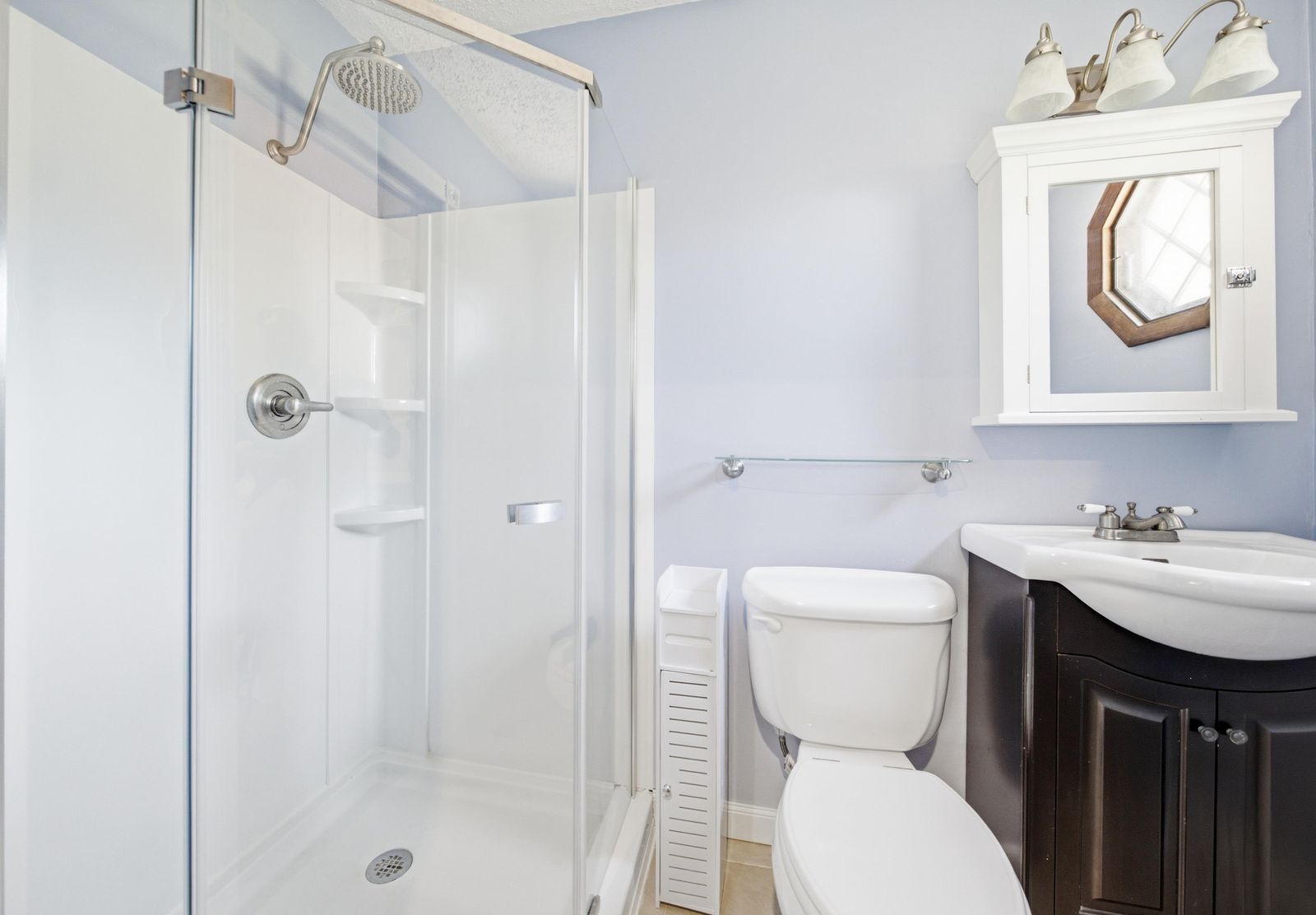 Bathroom with glass stall shower, rain shower head and dark vanity in Cape May Court House NJ