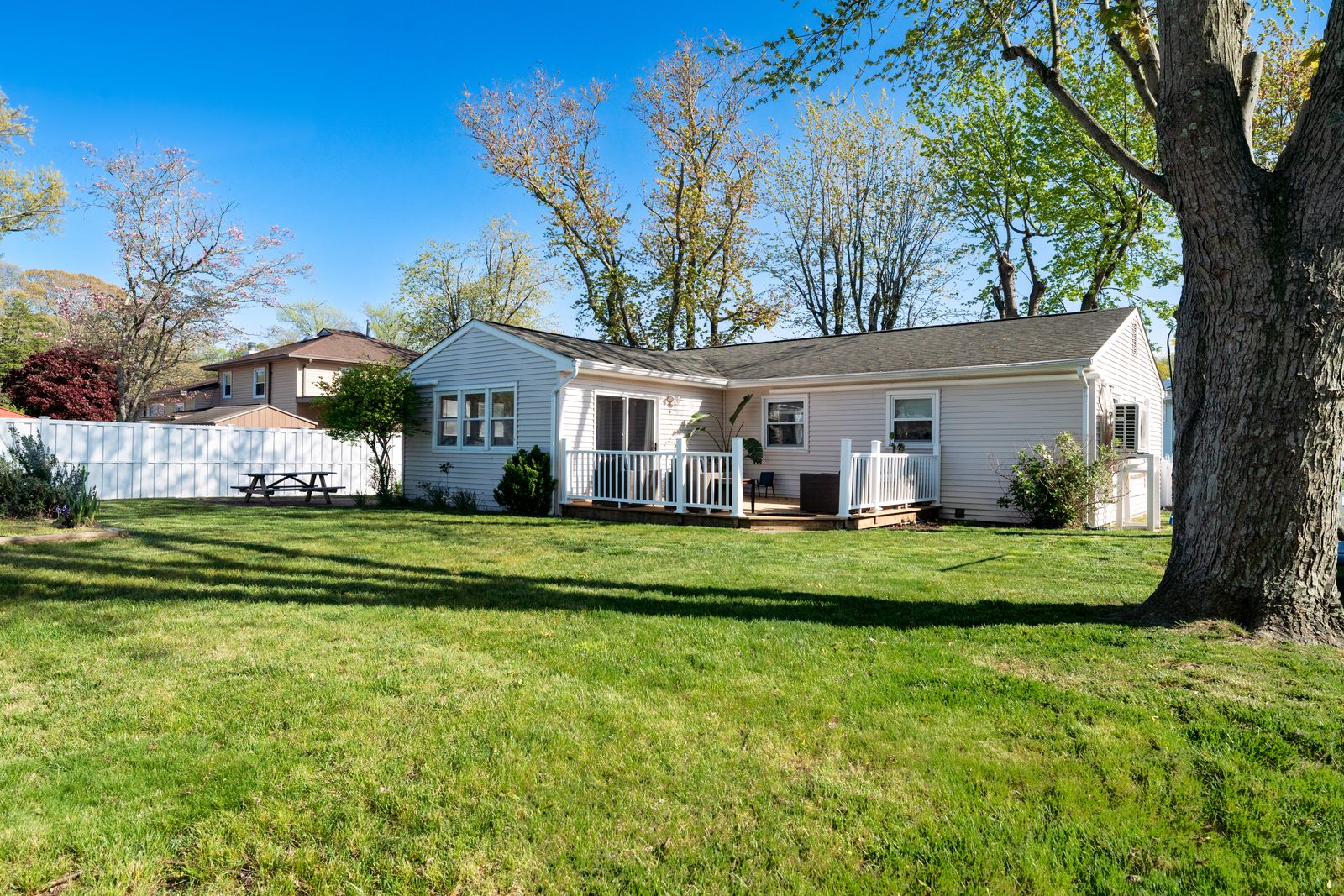 Back of the home with deck and big green lawn