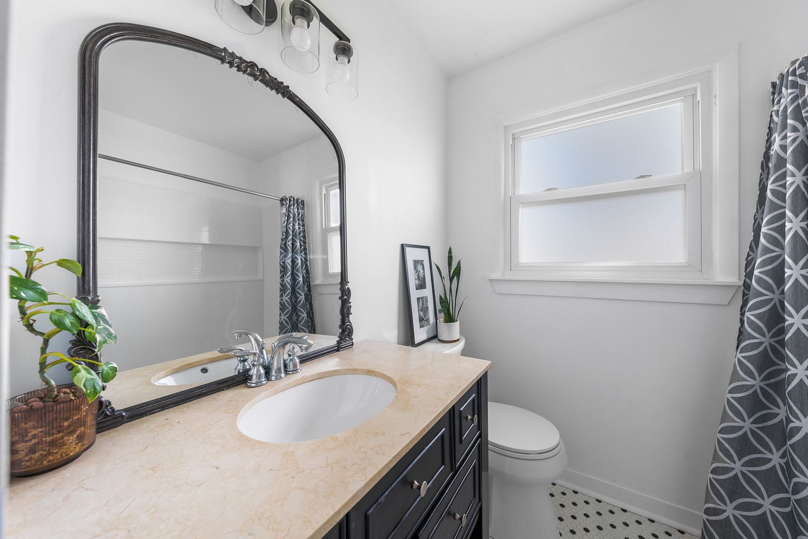 Updated bathroom with arched mirror and dark vanity