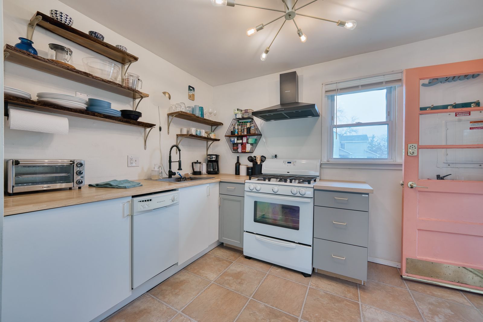 White kitchen with open wood shelving and gas range