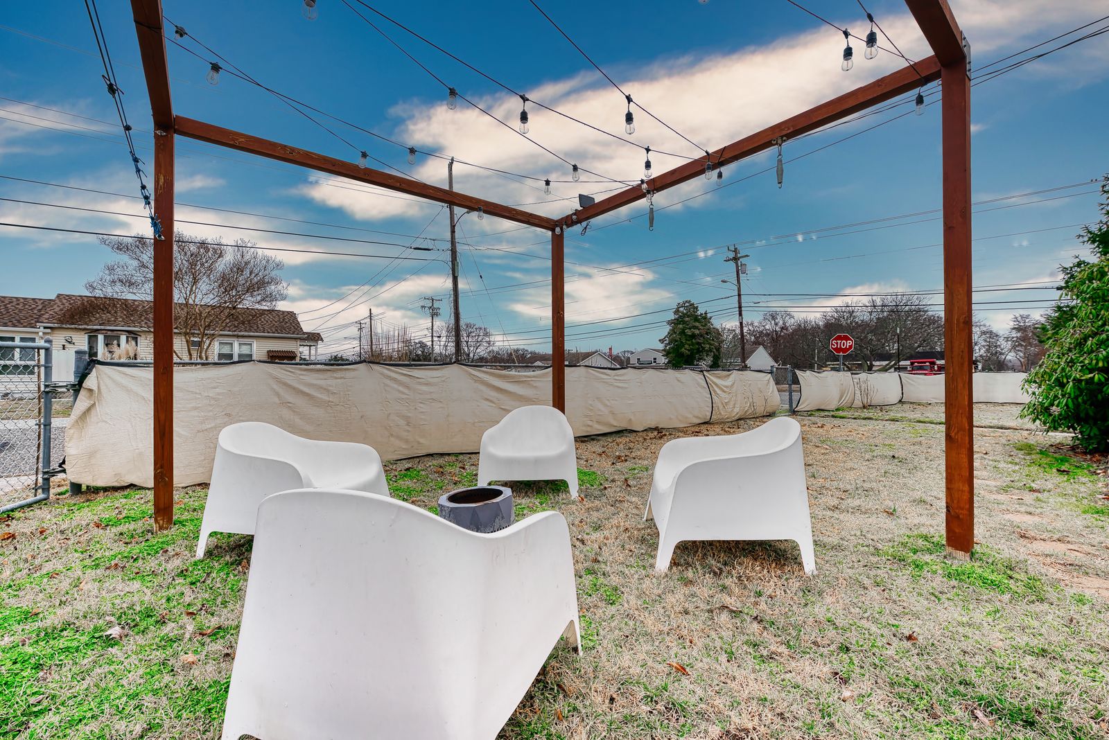 Backyard pergola with string lights and lounge chairs