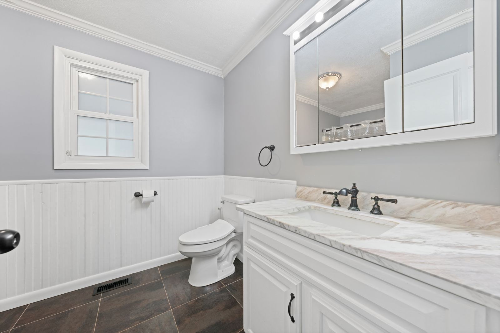 Bathroom with marble vanity and wainscoting