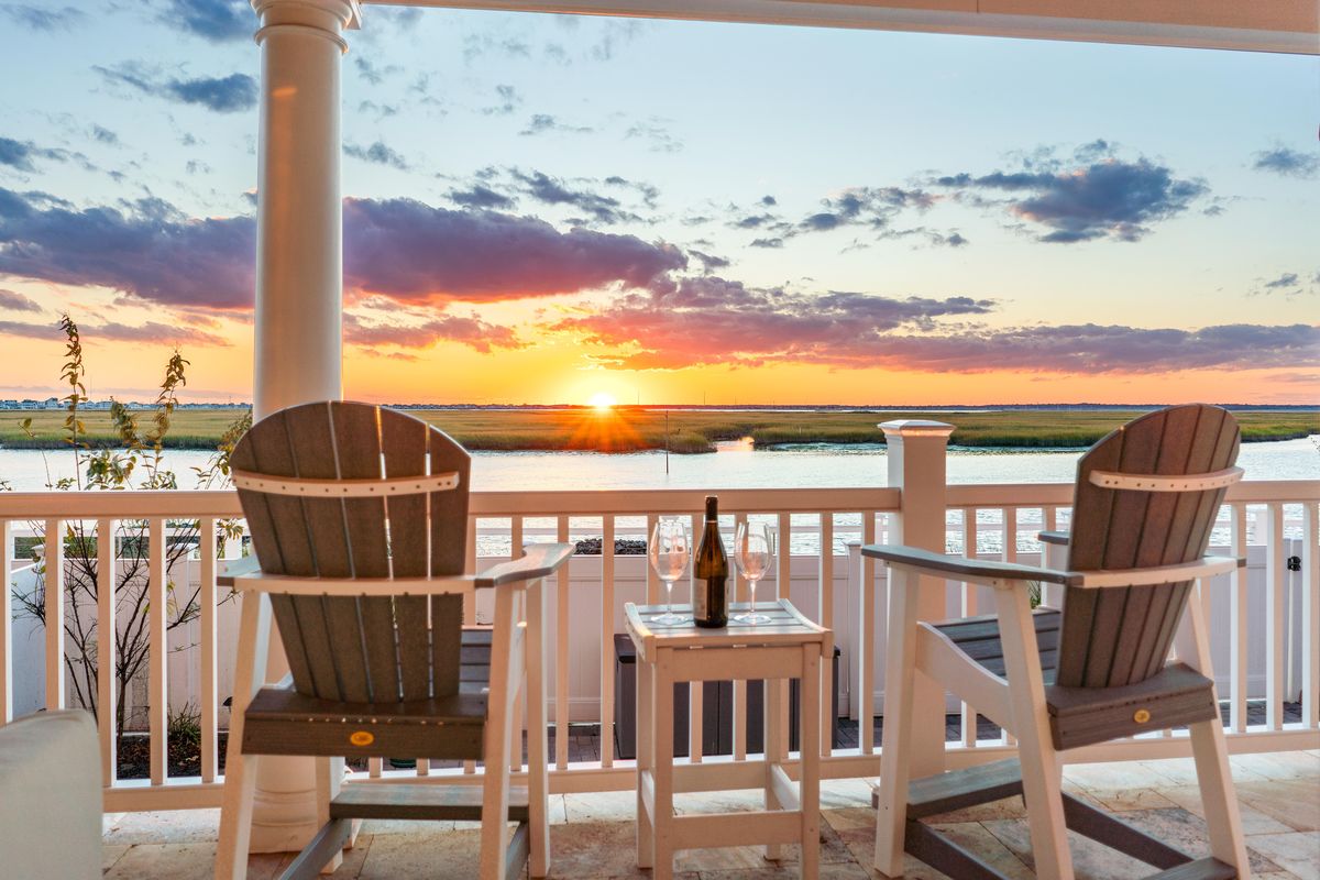 Adirondack chairs facing the sunset over the bay
