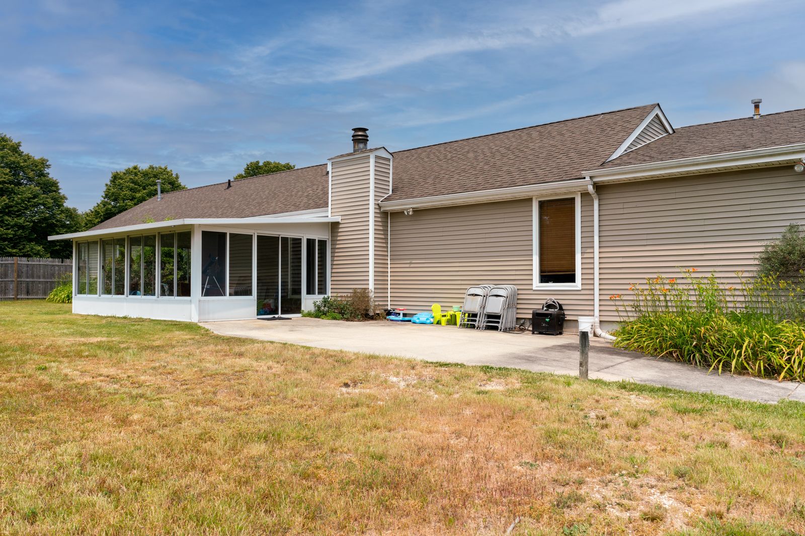 Back of the home with sunroom and lawn