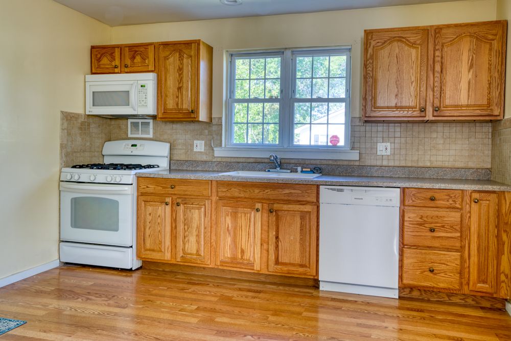 Oak kitchen with tile backsplash and white appliances