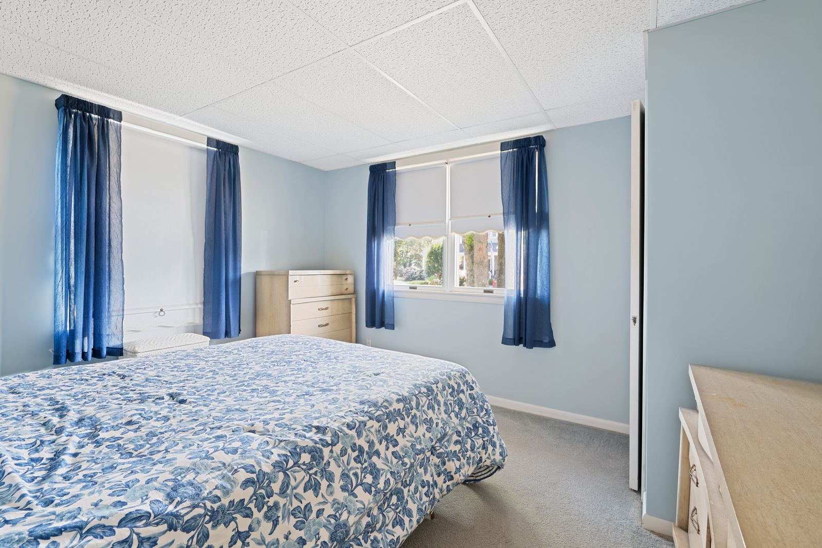 Bedroom with blue curtains and two windows