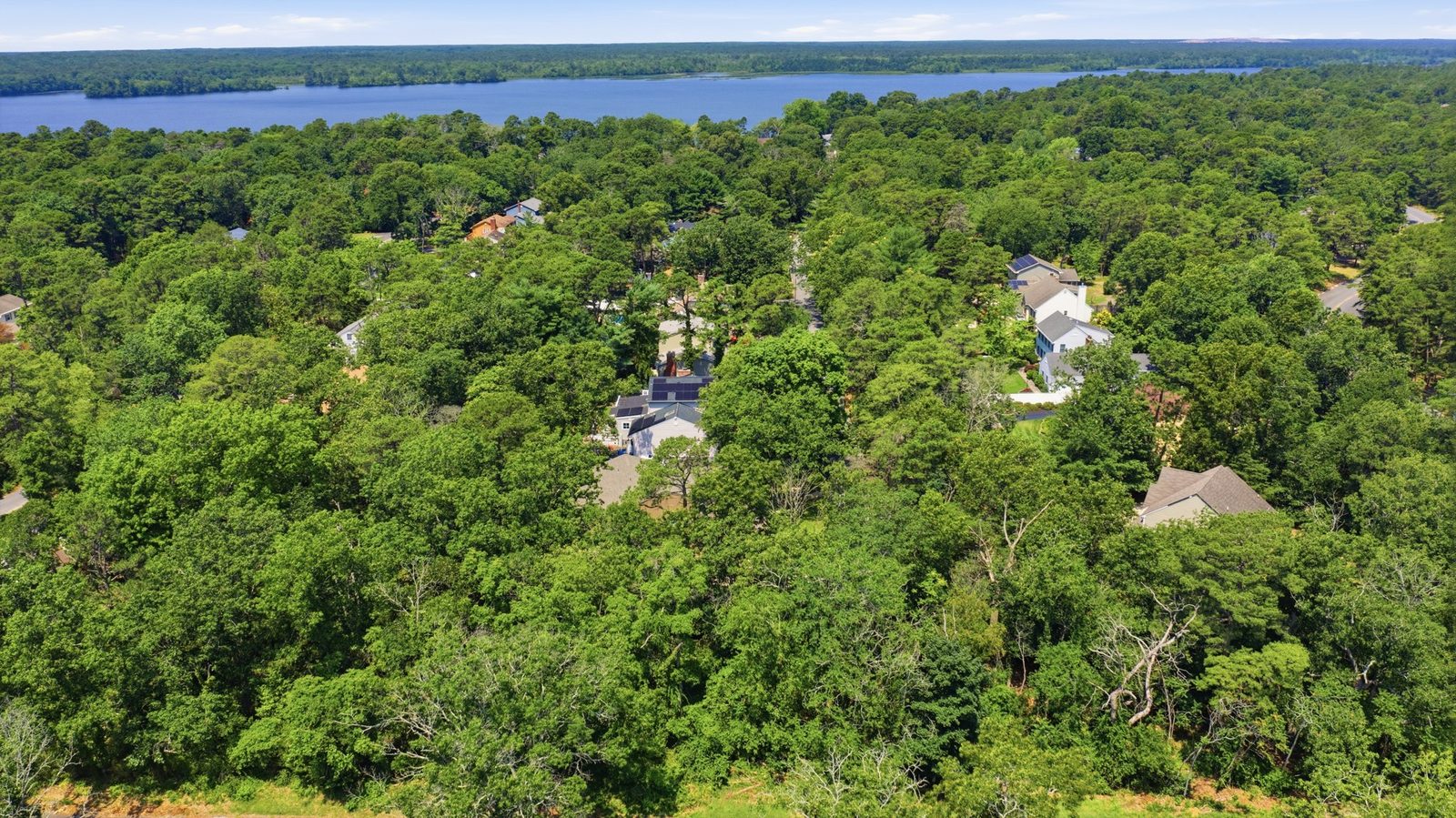 Drone view of a wooded lake lot with a home in Millville NJ